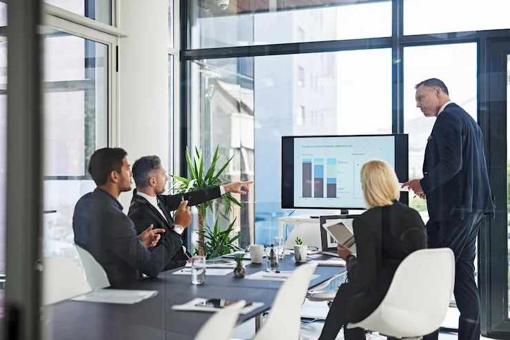 Colleagues in a meeting room watching a chart presented on a wall screen
