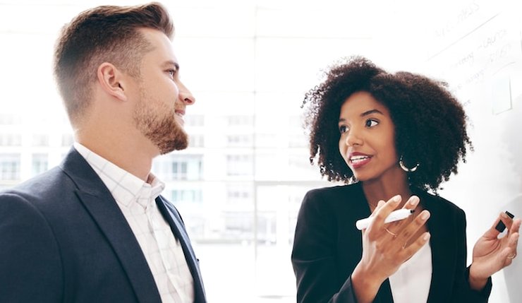 Two colleagues talking in front of a whiteboard